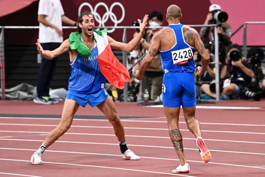 L'italiano Gianmarco Tamperi festeggia con il saltatore in alto Lamont Marcel Jacobs dopo aver vinto la finale dei 100 metri maschili alle Olimpiadi di Tokyo 2020 | Foto: Agenzia France-Presse