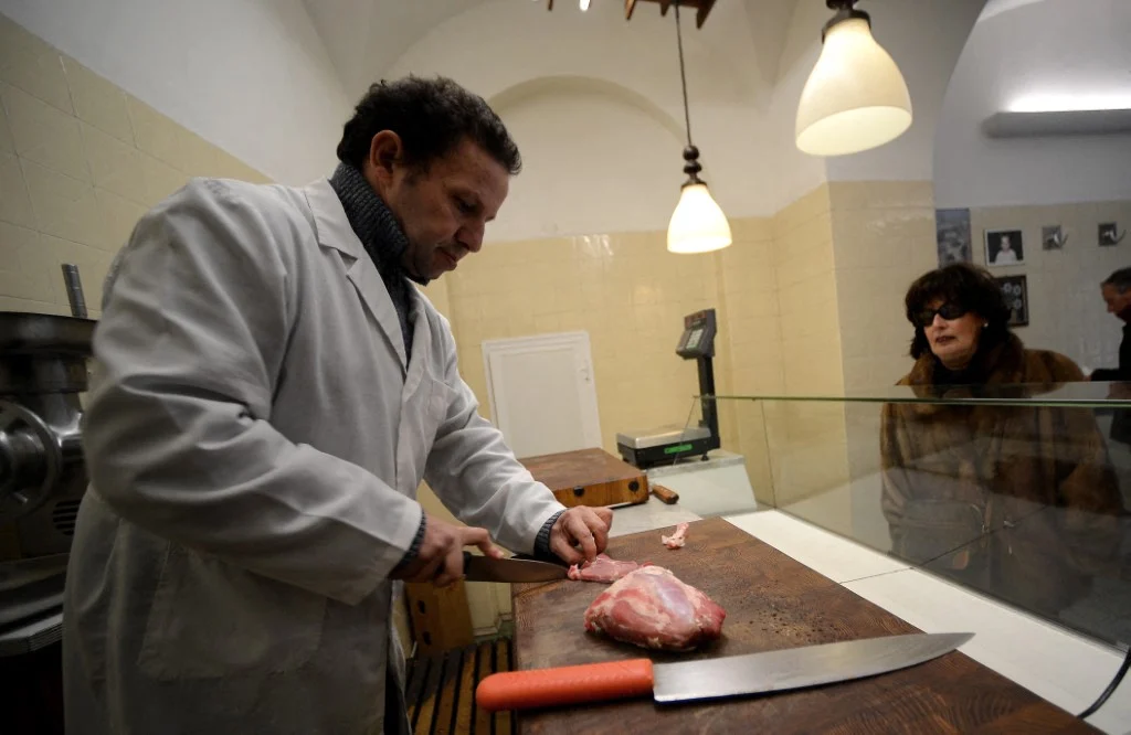 Um açougueiro atende um cliente em sua loja no centro de Roma em fevereiro de 2013. Foto de FILIPPO MONTEFORTE / AFP
