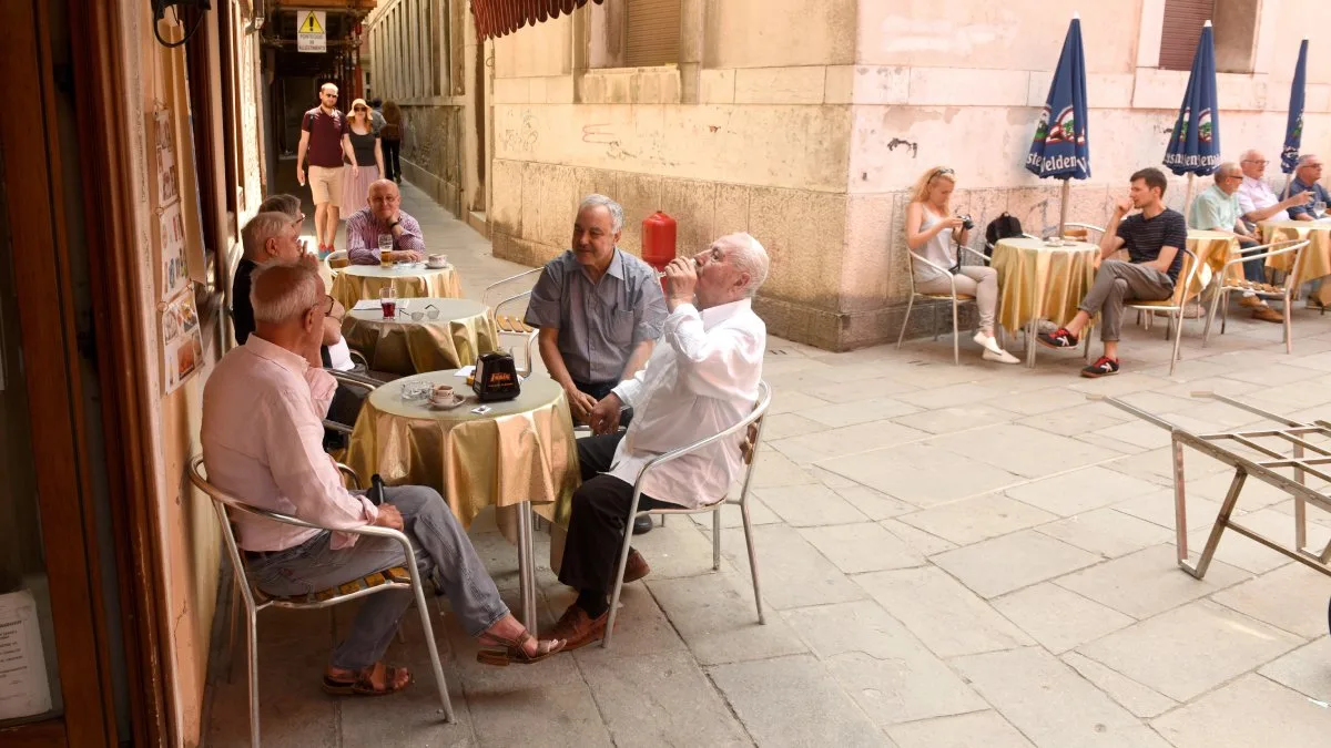 Idosos italianos reunidos em um café ao ar livre em Veneza, destacando a importância do convívio social para a longevidade | Foto: Depositphotos