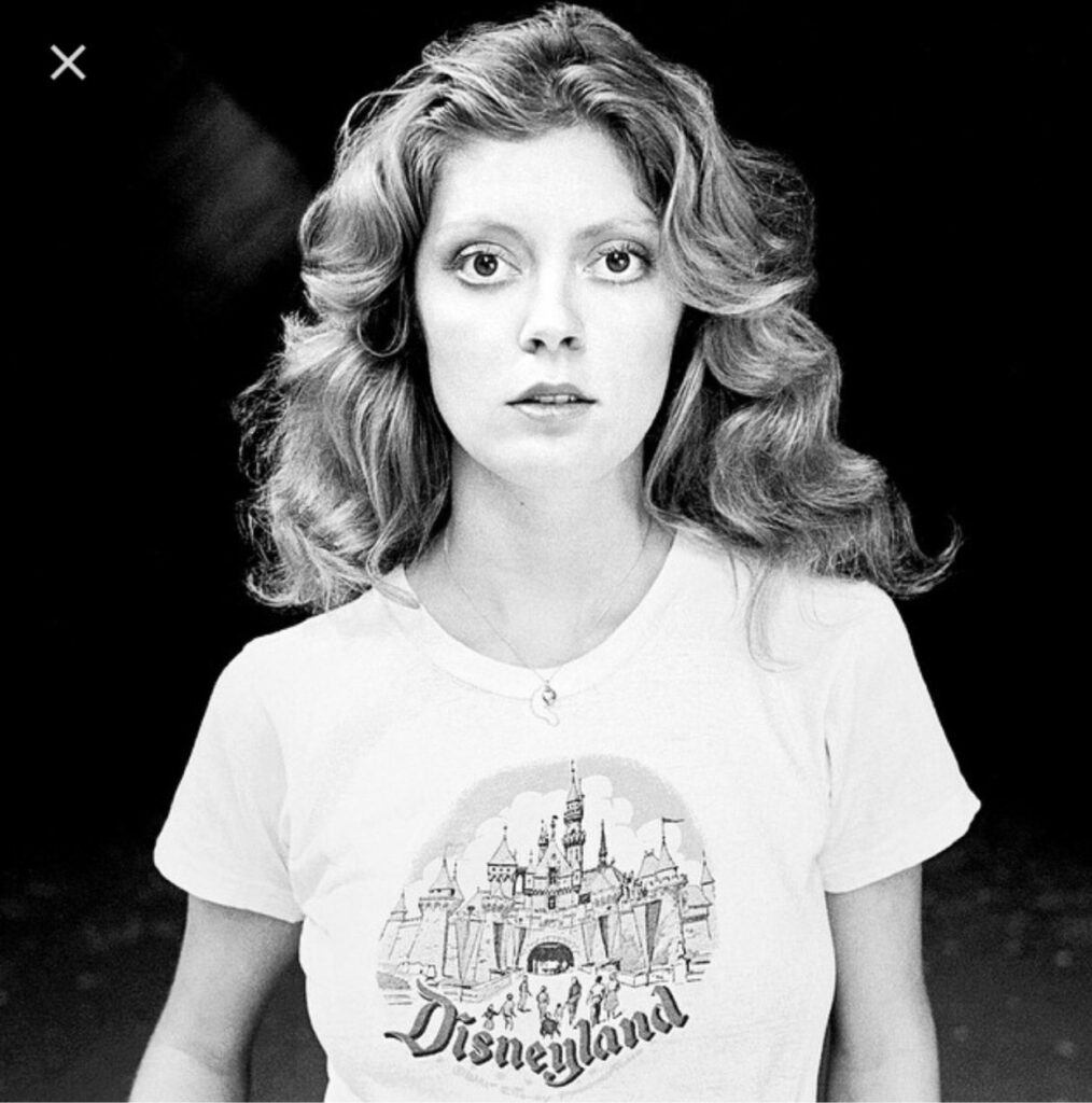 Susan Sarandon em um ensaio fotográfico da década de 1970, vestindo uma camiseta com estampa da Disneylândia