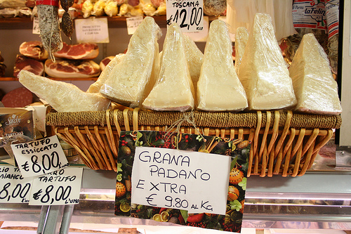 Grana Padano à venda em mercado tradicional italiano: sabor mais suave e maturação mais curta em relação ao Parmigiano Reggiano