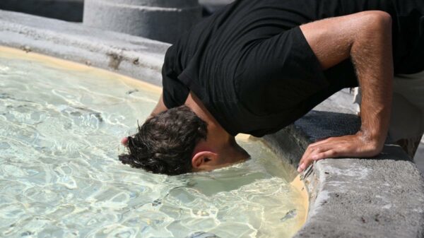 Homem se refresca na fonte da Piazza del Popolo, em Roma | Foto: Tiziana FABI / AFP