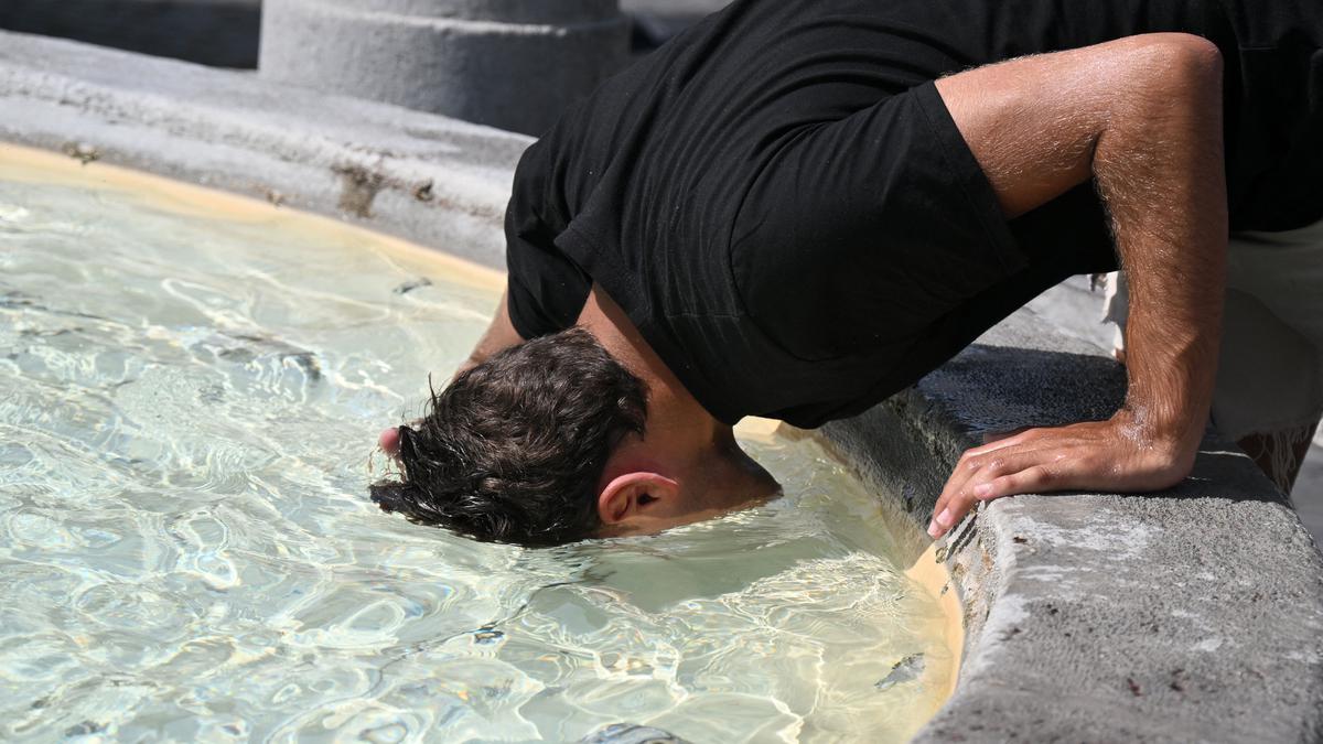 Homem se refresca na fonte da Piazza del Popolo, em Roma | Foto: Tiziana FABI / AFP