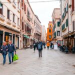 Casal caminha por rua comercial em Veneza, cidade muito procurada por estrangeiros que desejam investir em imóveis na Itália | Foto: Depositphotos