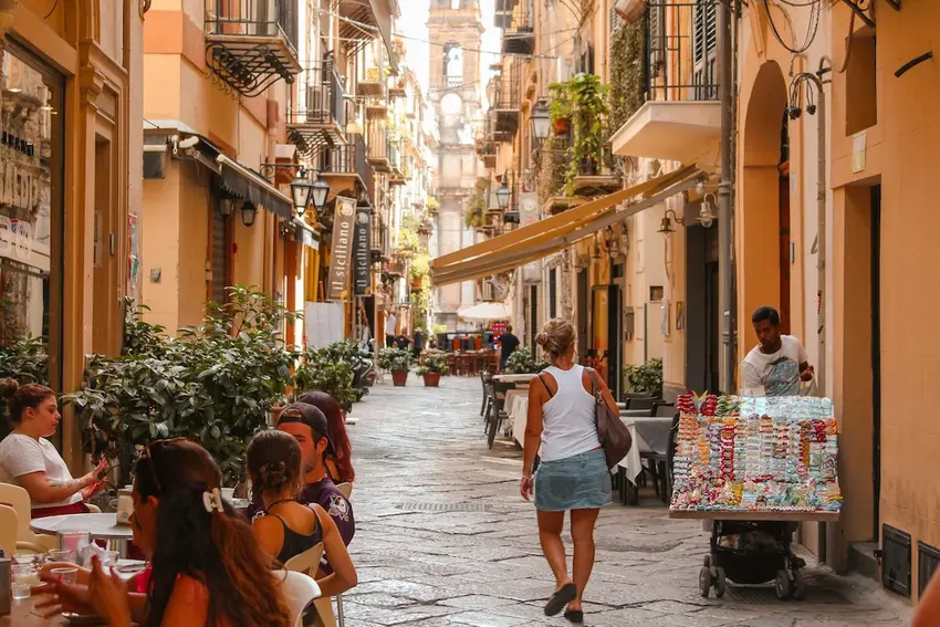 Turista caminha por rua histórica de Palermo, na Sicília, popular entre estrangeiros que visitam ou possuem imóveis na Itália | Foto: Unsplash
