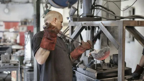 rabalhador opera máquina em indústria metalúrgica na Itália, setor que contribui para a recuperação do emprego no país