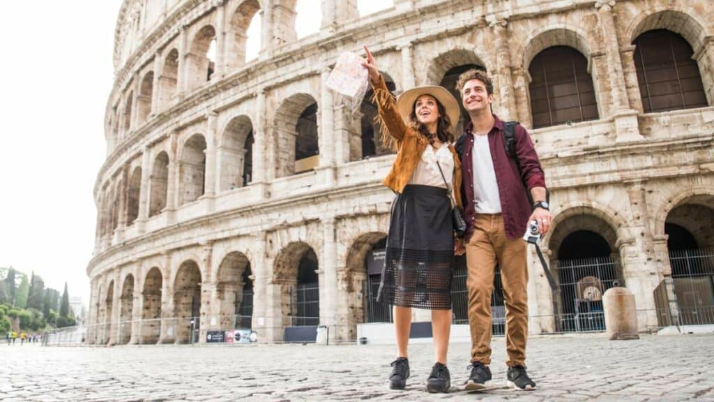 Casal de turistas observa o Coliseu, em Roma, durante passeio pelo principal símbolo da capital italiana.