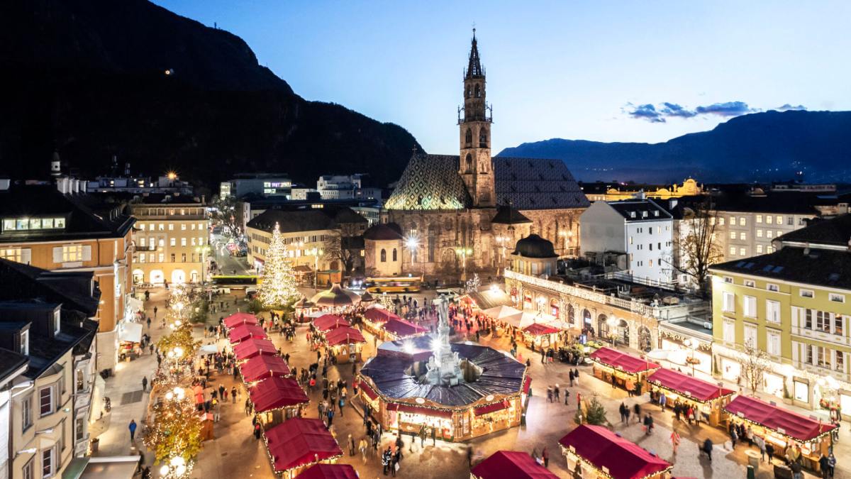 A tradicional Piazza Walther, em Bolzano, recebe os chalés do mercadinho de Natal, decorada com luzes e a árvore dos desejos.