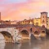 Ponte Pietra ao entardecer, em Verona, com o rio Ádige e o centro histórico ao fundo. A cidade italiana conquistou o 4º lugar no European Best Destinations 2026.