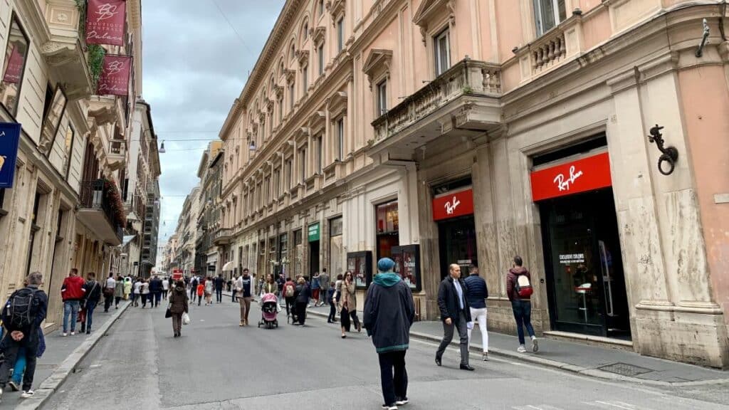 Pedestres caminham pela Via del Corso, no centro de Roma. A rua concentra parte do comércio que reduz o horário no feriado de 2 de junho.