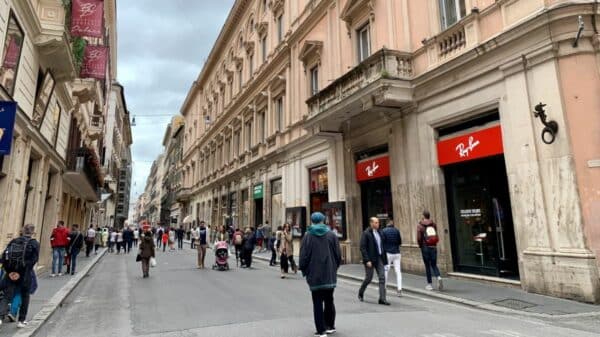 Pedestres caminham pela Via del Corso, no centro de Roma. A rua concentra parte do comércio que reduz o horário no feriado de 2 de junho.