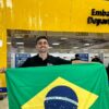 Passageiro exibe a bandeira nacional antes de embarcar no Aeroporto de Guarulhos (GRU), principal porta de saída dos brasileiros que emigram