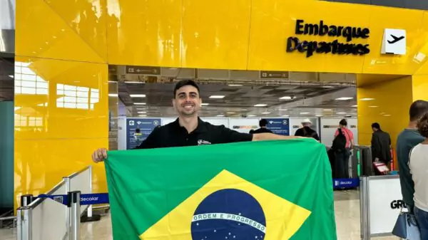 Passageiro exibe a bandeira nacional antes de embarcar no Aeroporto de Guarulhos (GRU), principal porta de saída dos brasileiros que emigram