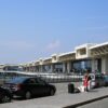 Fachada do Aeroporto de Malpensa, em Milão, com carros e passageiros em frente ao terminal.