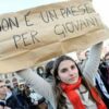 Jovem exibe cartaz onde se lê "Non è un paese per giovani" (não é um país para jovens), em ato de rua na Itália, símbolo do descontentamento que empurra a nova geração para o exterior.
