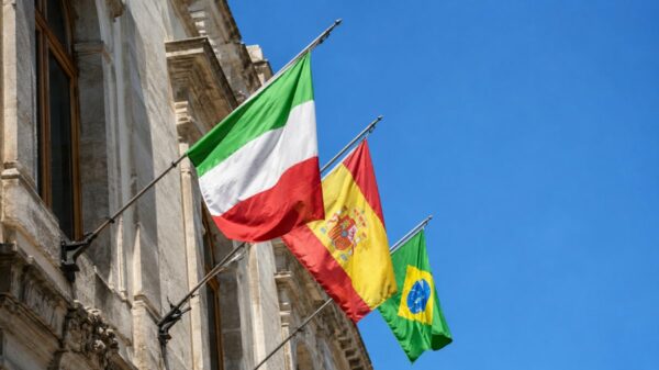 Bandeiras de Itália, Espanha e Brasil hasteadas em fachada de edifício sob céu aberto | Imagem feita com IA