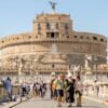 Turistas caminham pela Ponte Sant’Angelo, em Roma, com o Castel Sant’Angelo ao fundo. Também conhecido como Mausoléu de Adriano, o monumento foi posteriormente utilizado como fortaleza e castelo pelos papas. Foto: Depositphotos