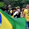 Flávio Bolsonaro discursa diante de apoiadores, com a bandeira do Brasil