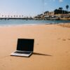 Notebook na areia em Cascais, Portugal, destino procurado por profissionais que trabalham remotamente | Foto: Depositphotos