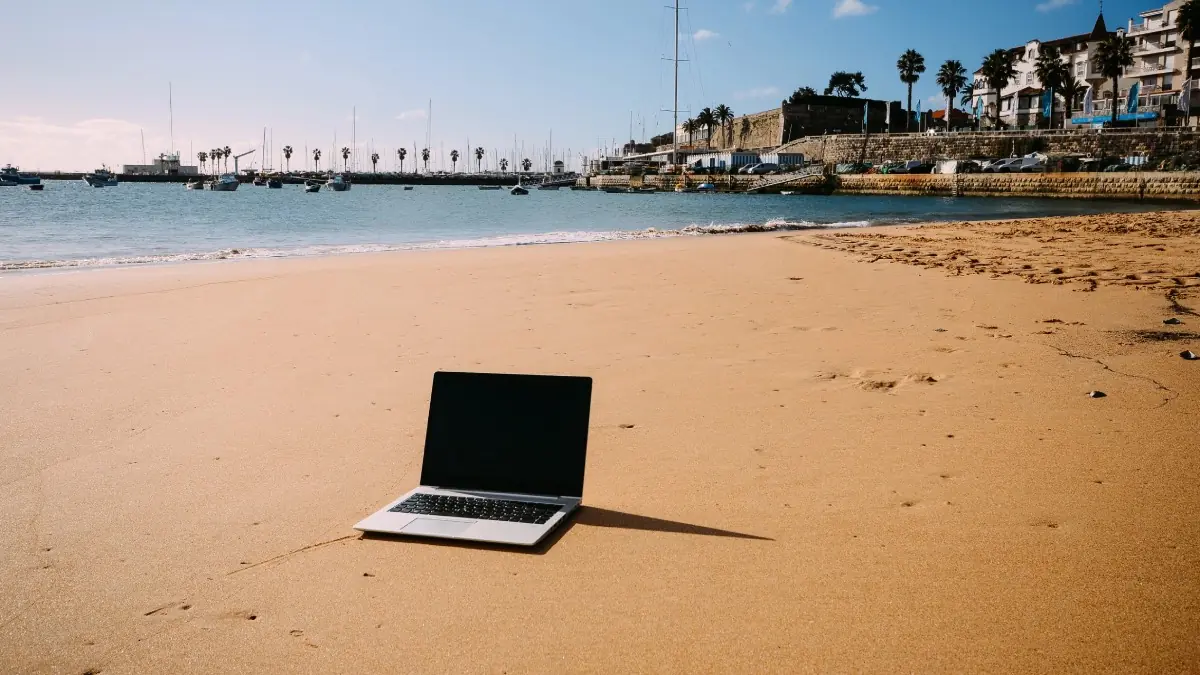 Notebook na areia em Cascais, Portugal, destino procurado por profissionais que trabalham remotamente | Foto: Depositphotos