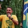 Flávio Bolsonaro discursa durante manifestação, ao lado de um retrato do ex-presidente Jair Bolsonaro | Foto: Reprodução