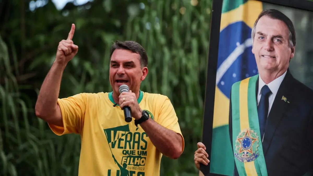 Flávio Bolsonaro discursa durante manifestação, ao lado de um retrato do ex-presidente Jair Bolsonaro | Foto: Reprodução