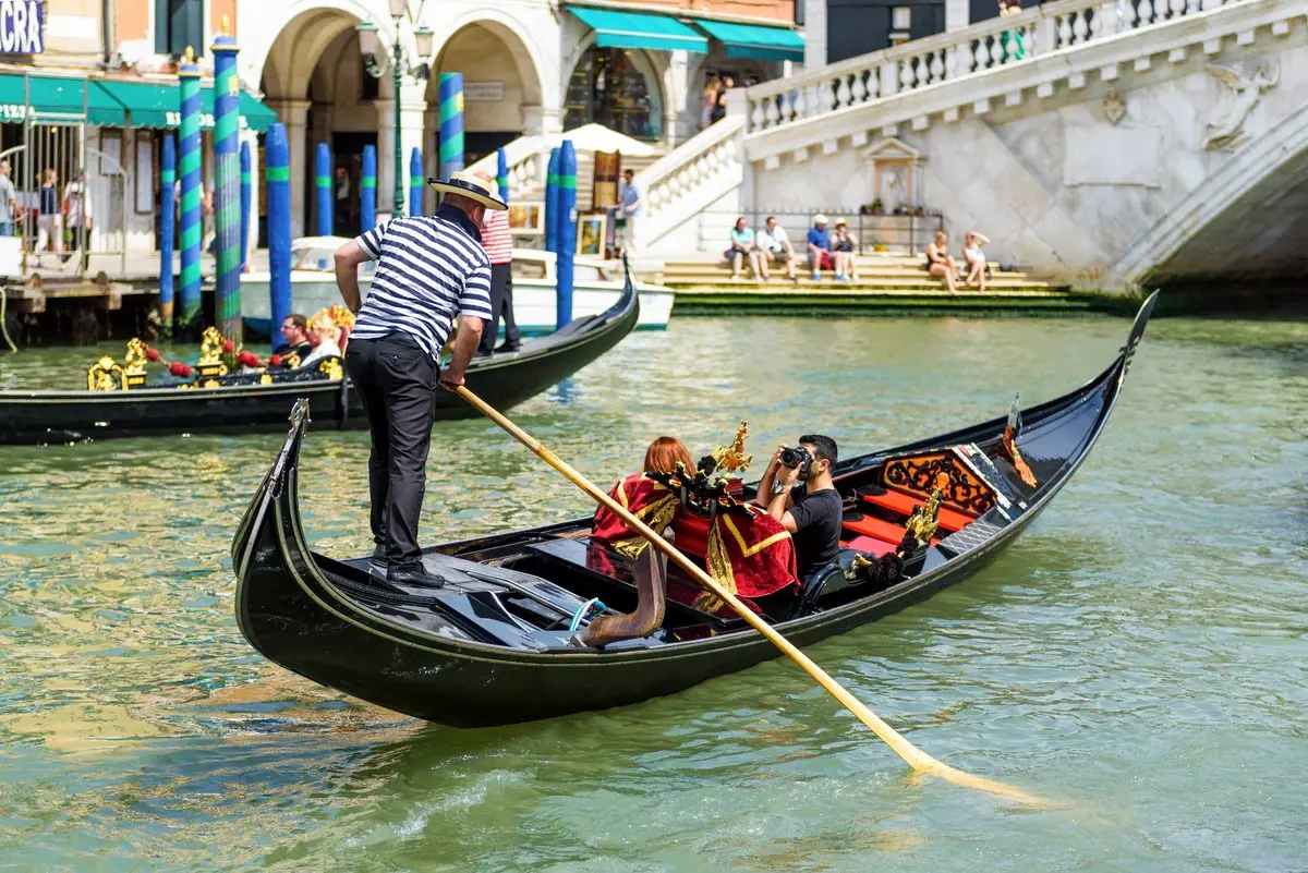 Gondoleiro conduz turistas pelo Grande Canal, perto da Ponte de Rialto, em Veneza
